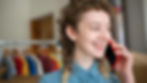 Smiling woman making a phone call in a bright indoor setting with blurred background.