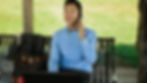 Asian businessman working remotely on phone with laptop in a sunny park.